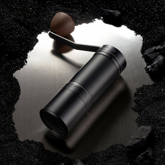 Black binoculars on a reflective surface with a dark, rocky background
