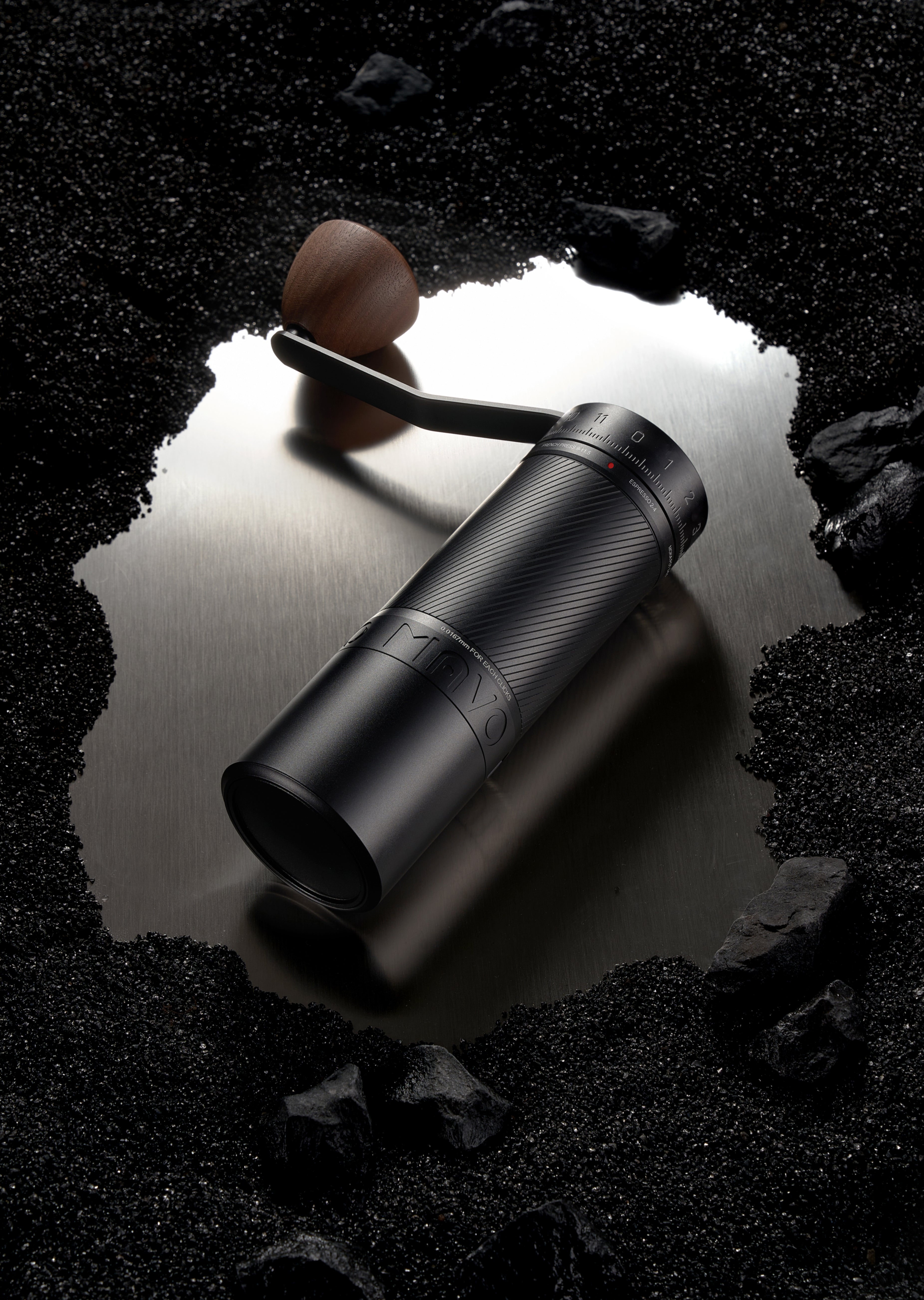 Black binoculars on a reflective surface with a dark, rocky background